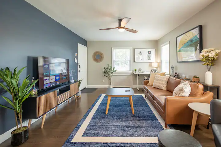 A panoramic view of a living room showcasing a central couch and a coffee table