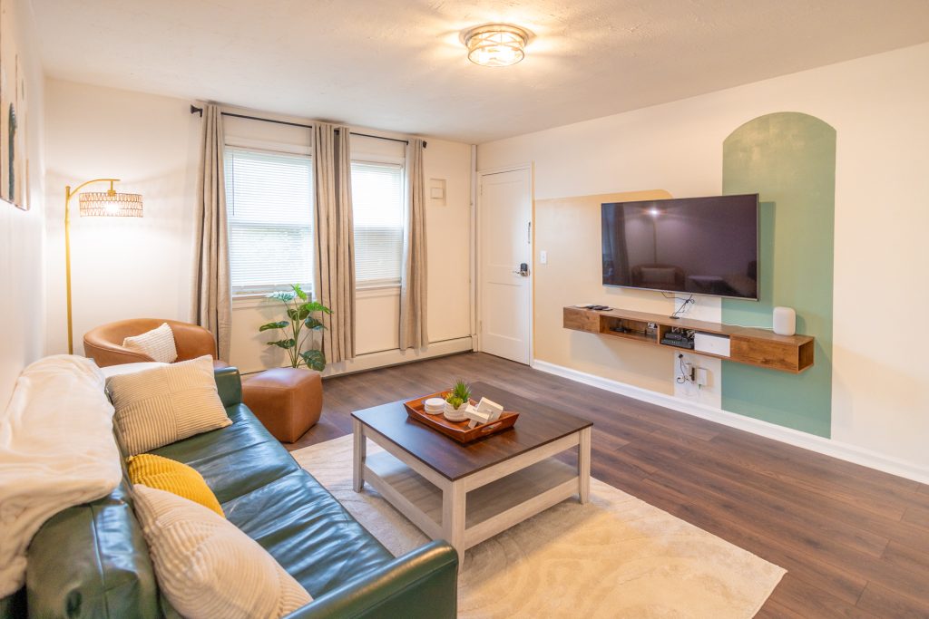 Bright and cozy living room with a white interior showcasing a soft couch, a chic coffee table, and a TV, perfect for unwinding and enjoying time together