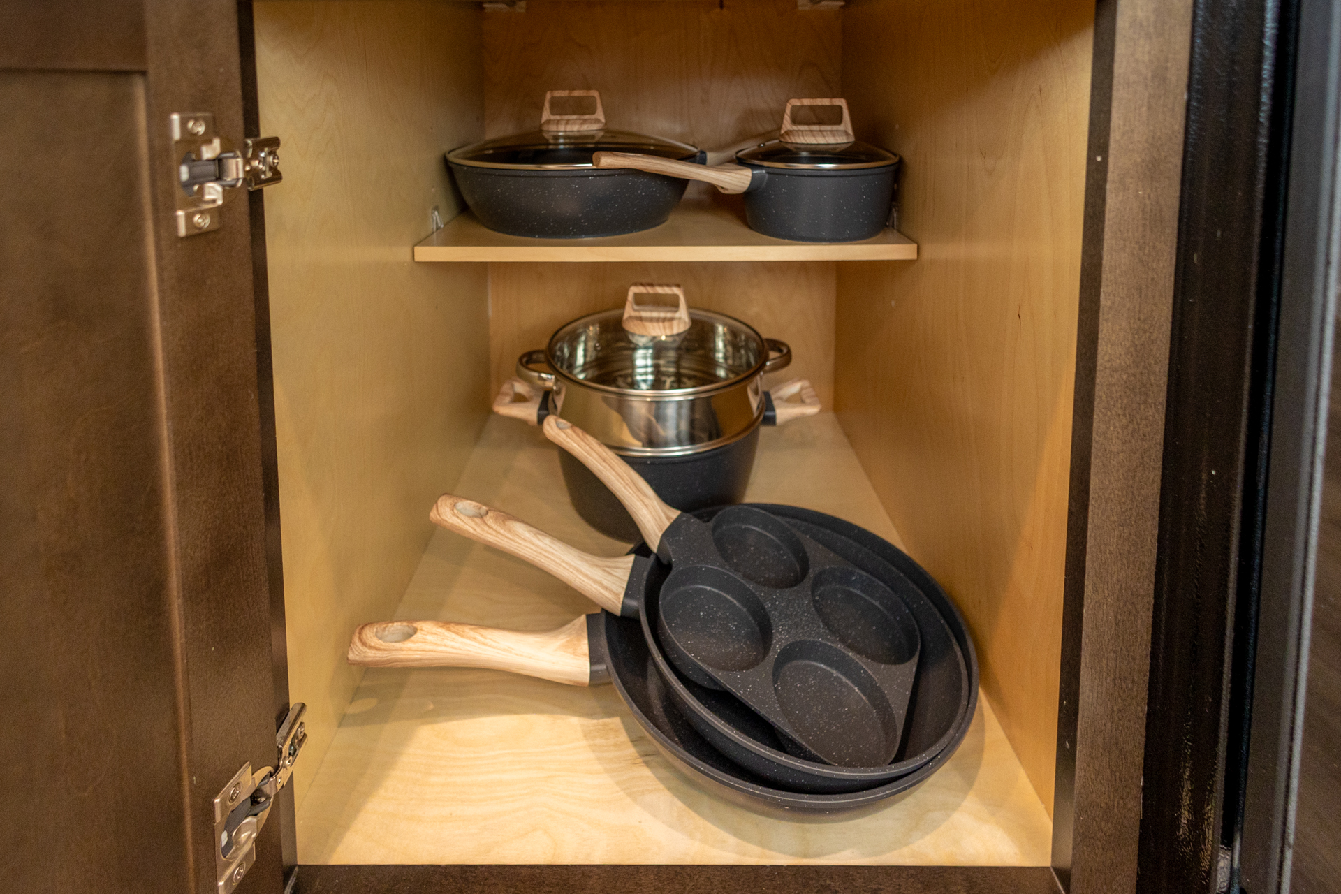 Cabinet with nonstick pans, skillets, and pots neatly stacked inside