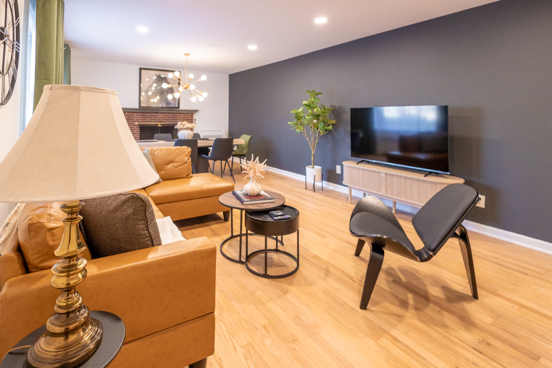 Bright living room with an L-shaped sofa, a shell chair, and a TV.