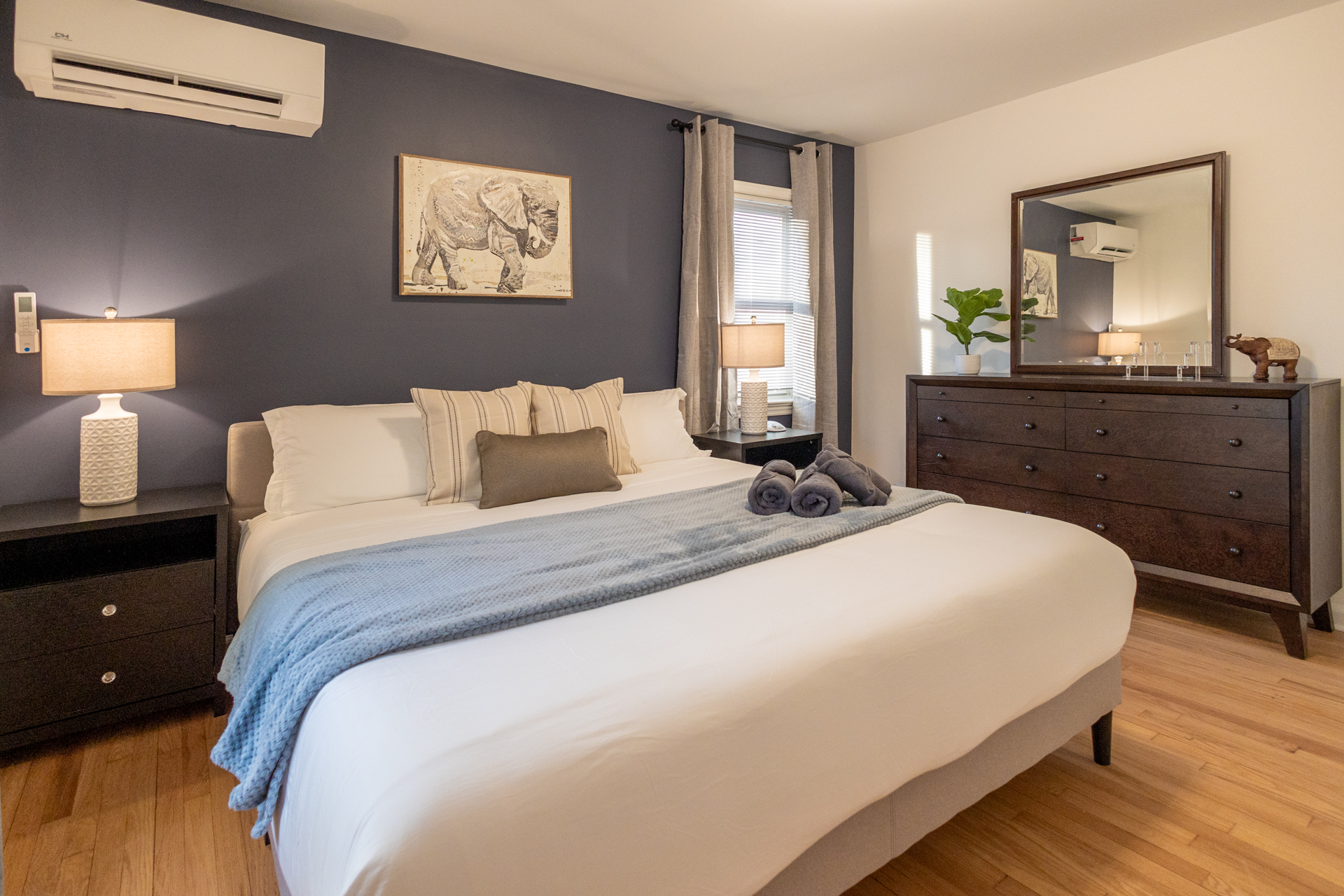 A cozy, modern bedroom featuring a navy accent wall, soft neutral bedding, warm lighting, and simple décor that creates a calm, inviting atmosphere.