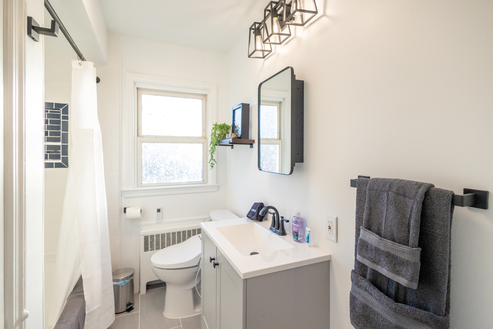 Featuring a sleek vanity, contemporary fixtures, and natural light from a frosted window, complete with a clean shower area and stylish towel storage.