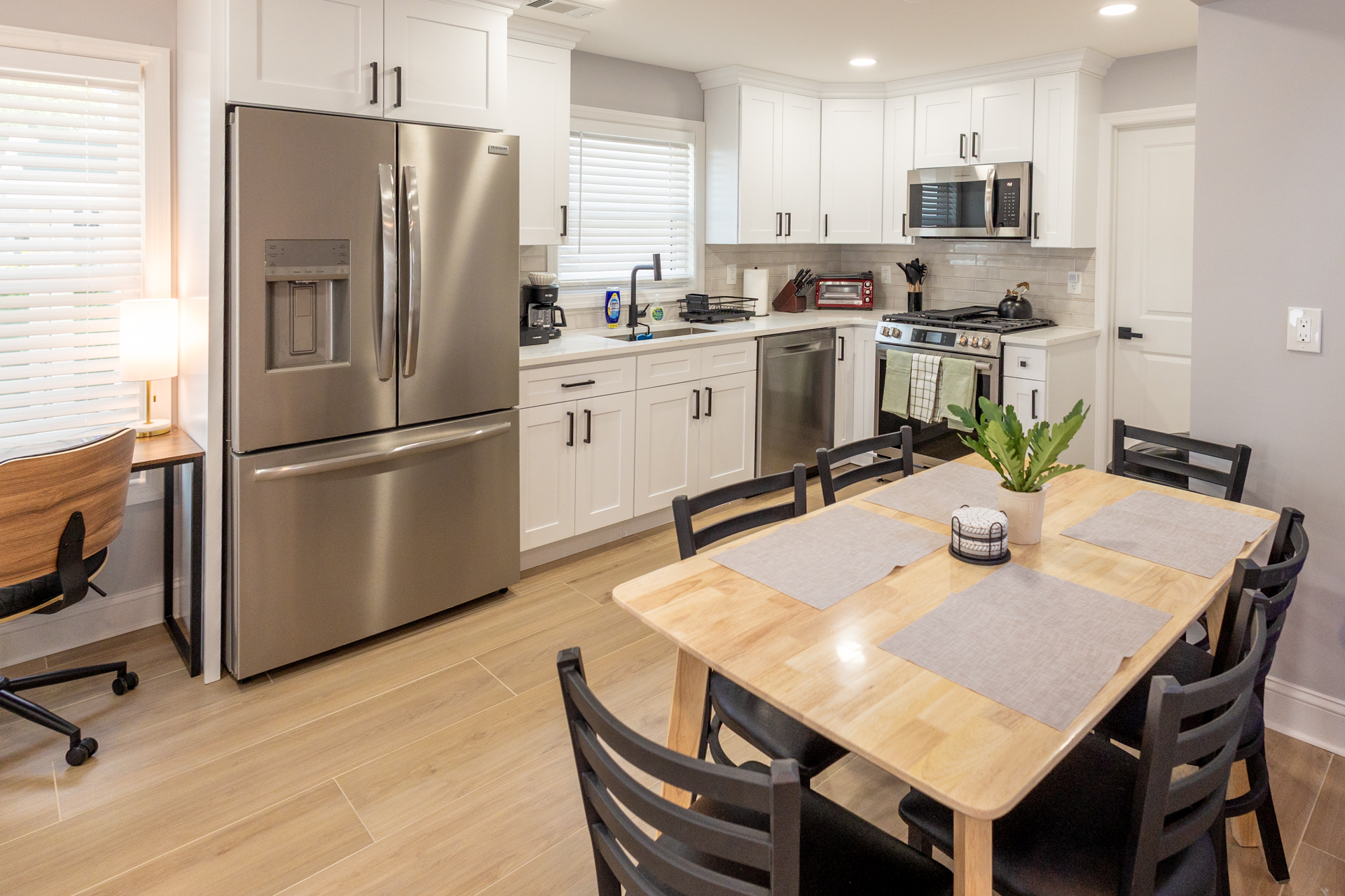 Open kitchen and dining area with modern appliances, ample cabinetry, and seating for four.