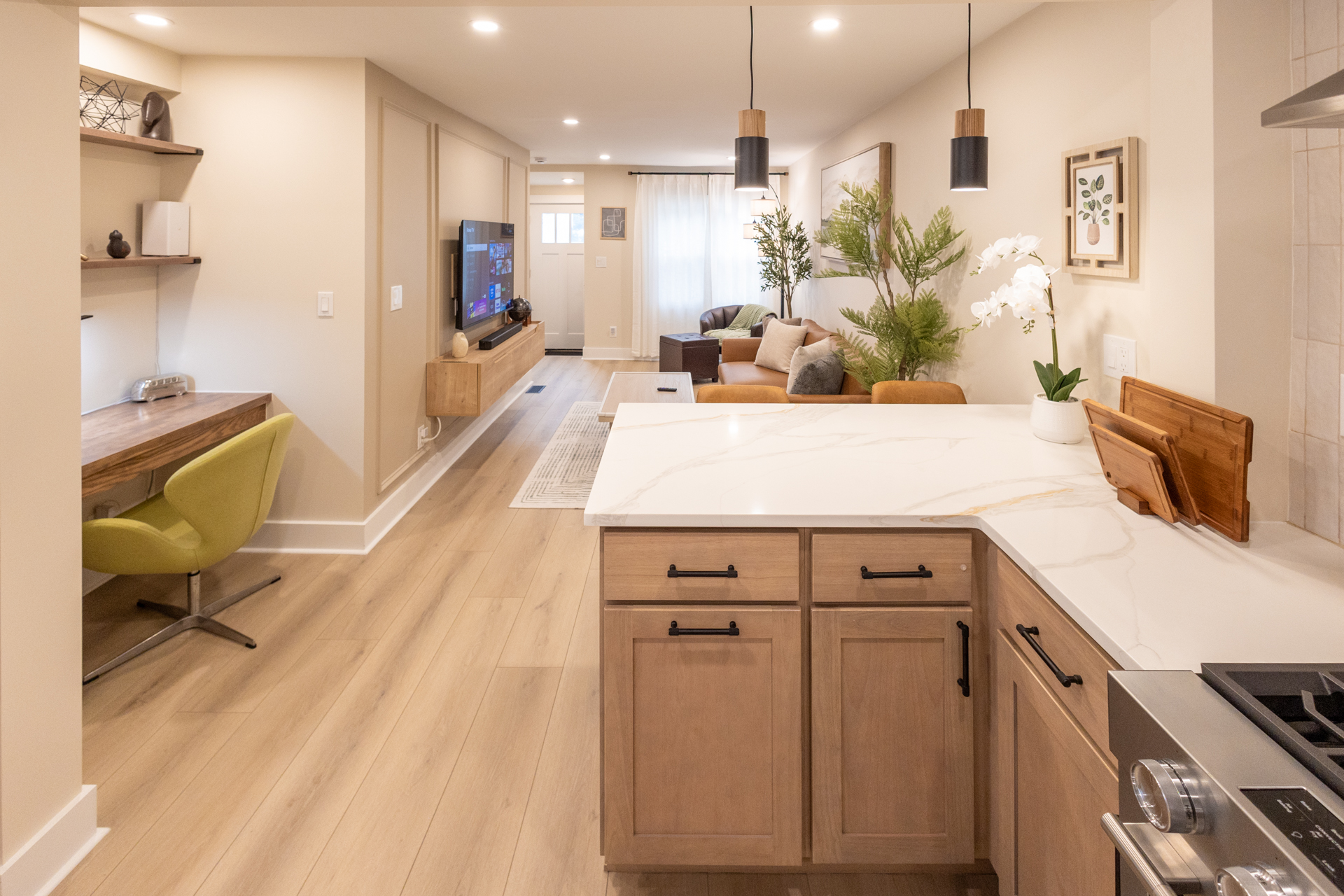 Open-concept interior with a kitchen island, wood cabinetry, dining area, and living room.