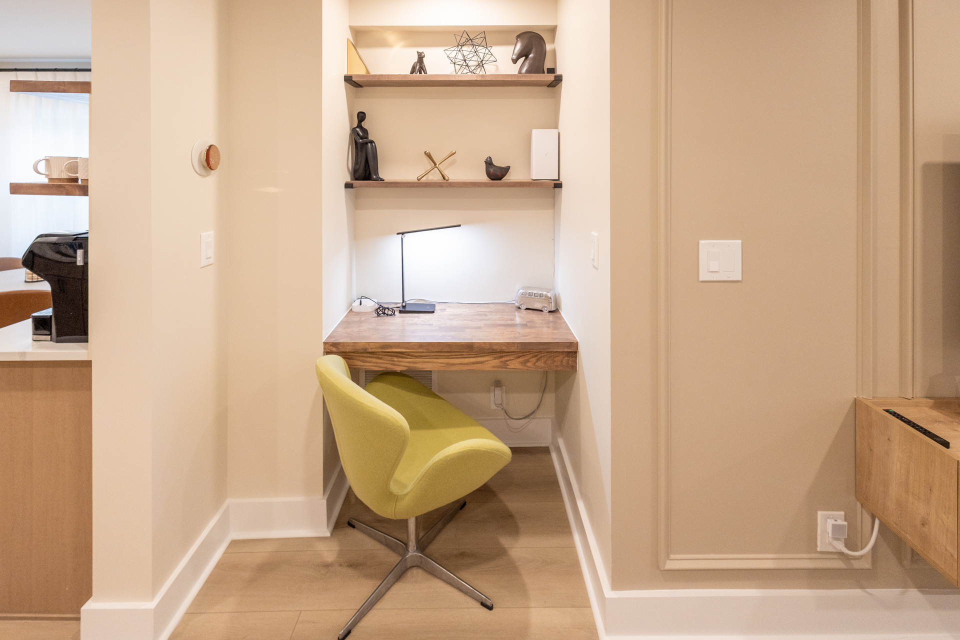 Compact workspace with a wooden desk, yellow chair, desk lamp, and built-in shelves.