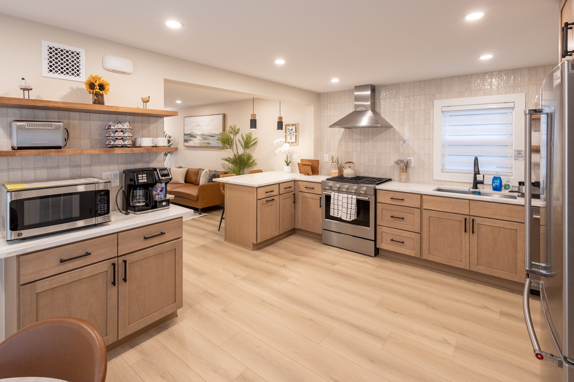 Bright modern kitchen with wood cabinetry, stainless steel appliances, and a spacious central island.