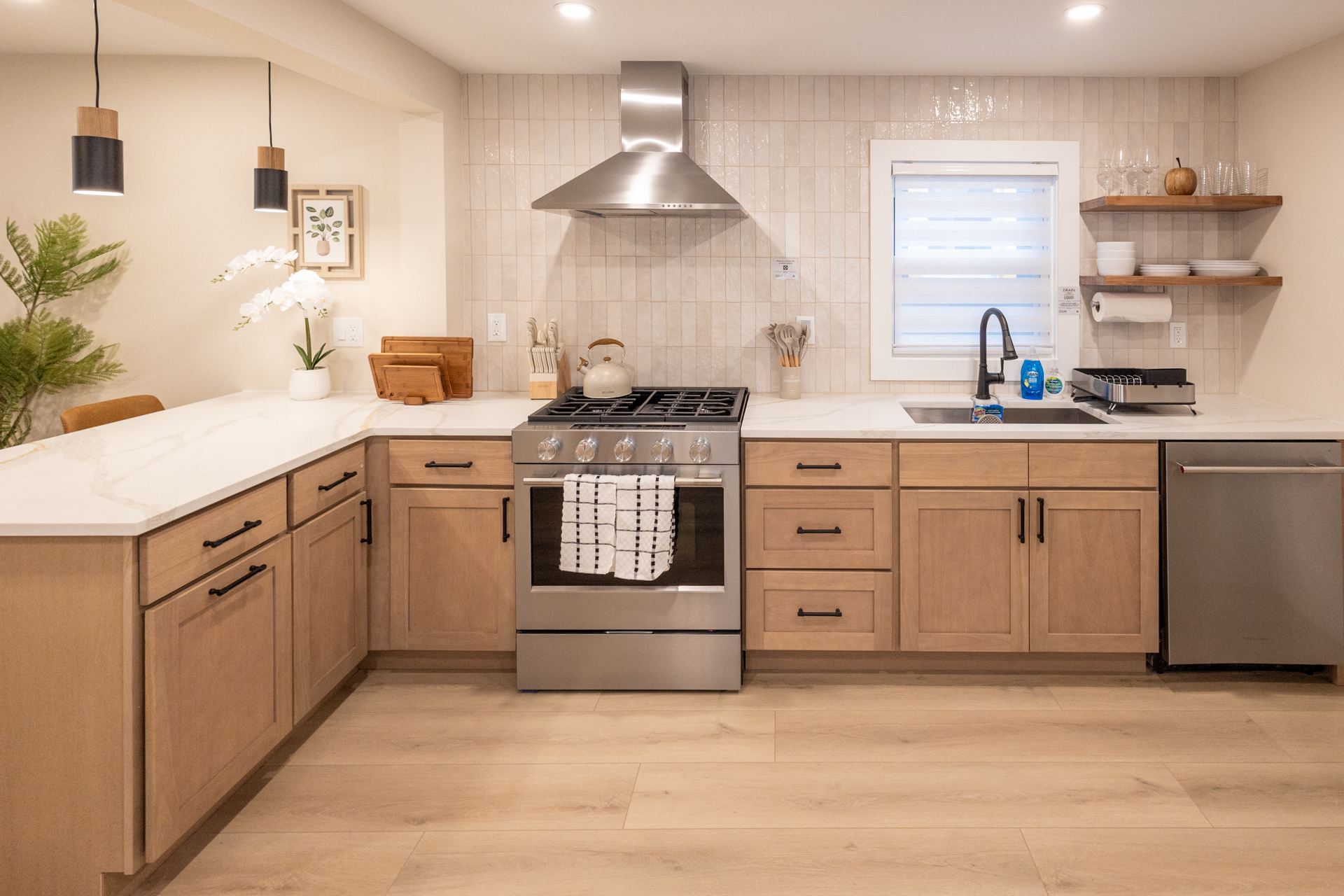 Bright kitchen with wood cabinets, stainless steel stove, sink, and ample counter space.