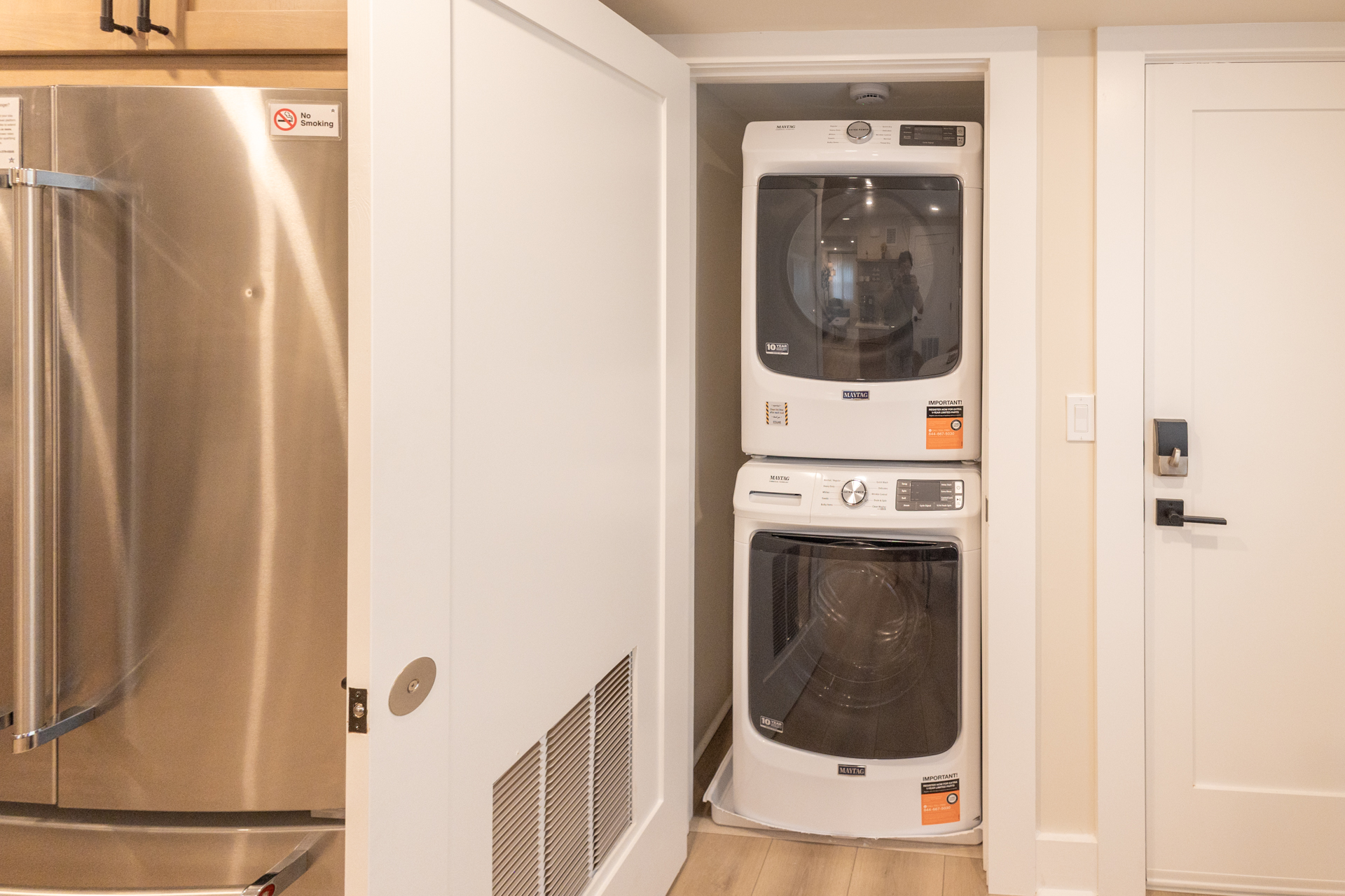 Closet with stacked washer and dryer next to the refrigerator.