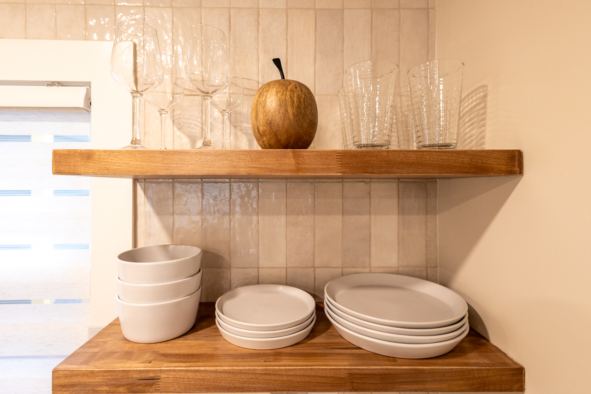 Wooden kitchen shelves with organized plates, bowls, and glassware.
